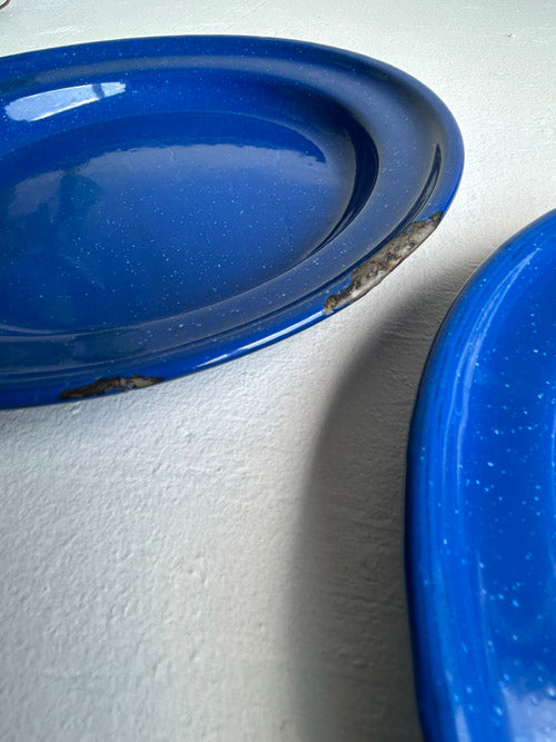 Two blue enamel plates on a white surface
