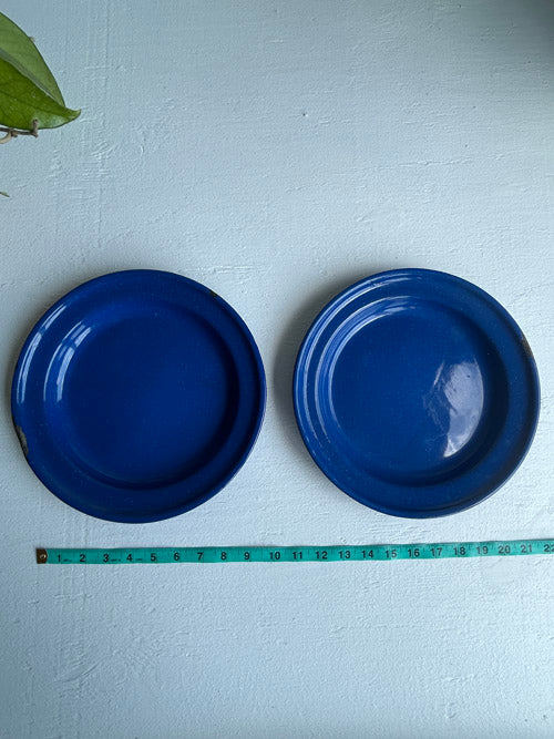 Two blue plates with a measuring tape for scale on a white background