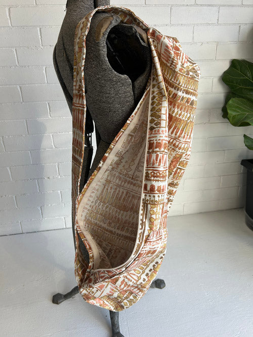 Mannequin wearing a vintage look patterned yoga mat bag with a white brick wall background