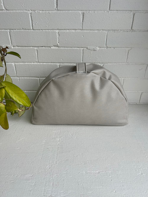 Gray meditation cushion on a light gray surface with a white brick wall background