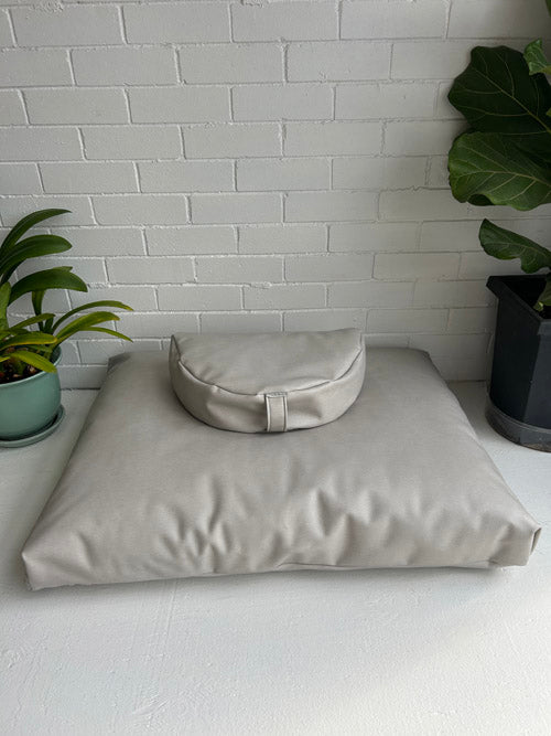Beige meditation pillows on a white surface with a white brick wall background