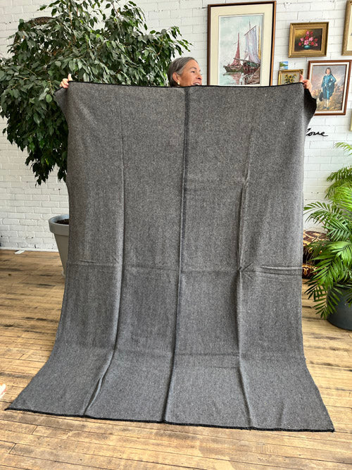Grey wool army blanket held up by a person